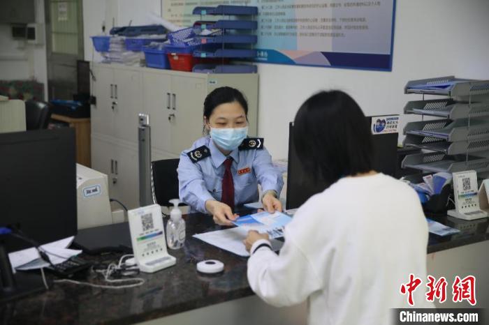 图为江门高新区税务人员向缴费人派发社保费缓交宣传小册子 杨伟 摄